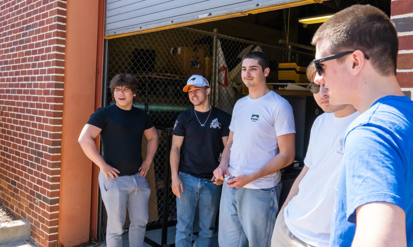 Nittany Motorsports team members from a variety of subsystems taking a break to enjoy some discussion and the warm sunny weather. On nice days the garage door is left open to fill the shop with natural light and fresh air.