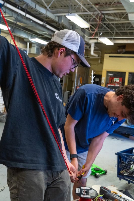 Low voltage subsystem members work together to make multiple cuts of wire the same length for creating a wiring harness.